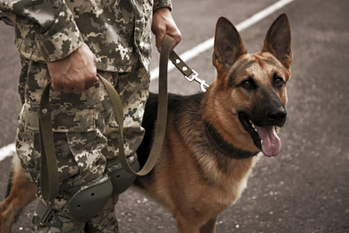 Image of Man in military uniform with German shepherd dog outdoors, closeup