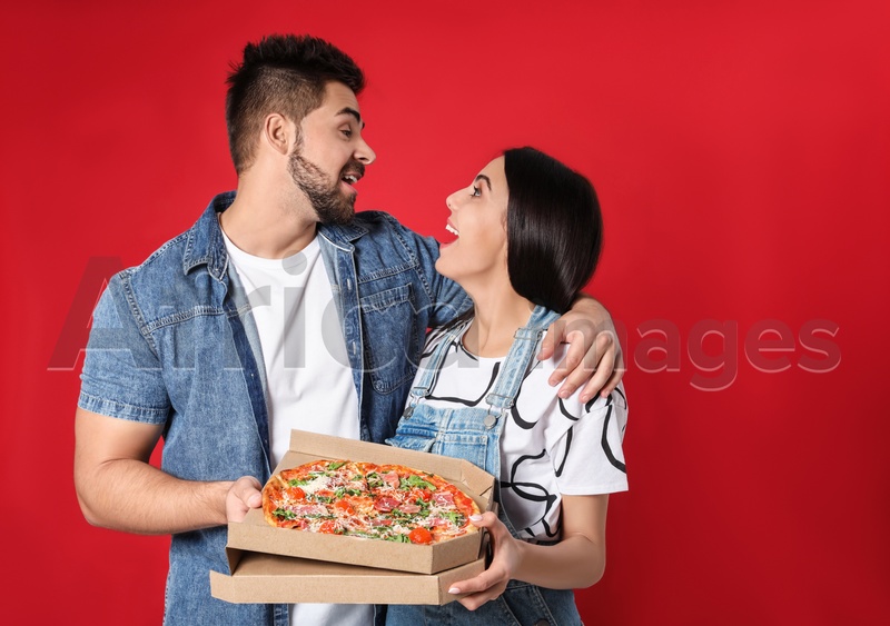 Photo of Emotional young couple with pizza on red background