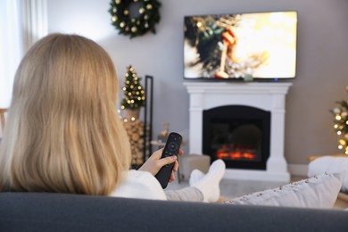 Woman watching TV in room decorated for Christmas