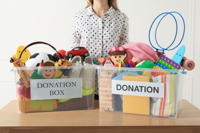 Woman near donation boxes with child toys against white background, closeup