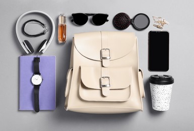 Stylish urban backpack with different items on grey background, flat lay