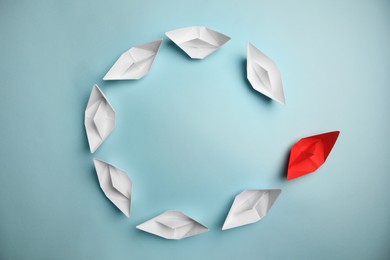 Photo of Group of paper boats following red one on light background, flat lay with space for text. Leadership concept