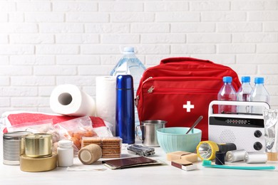 Disaster supply kit for earthquake on white wooden table near brick wall