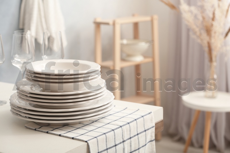 Photo of Set of clean dishware and wineglasses on white table indoors. Space for text