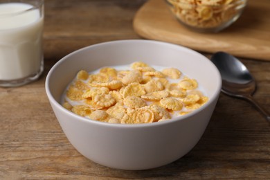 Tasty cornflakes with milk in bowl on wooden table