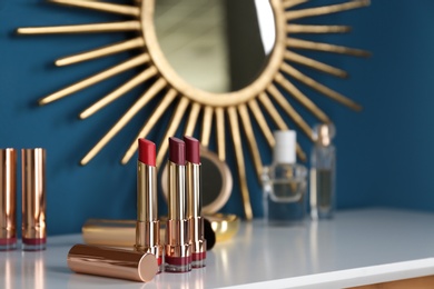Open bright lipsticks on dressing table, space for text