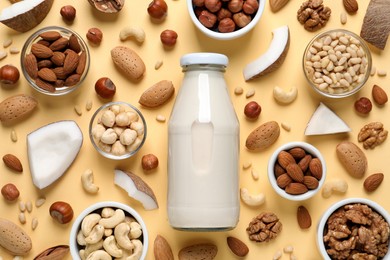 Vegan milk and different nuts on beige background, flat lay