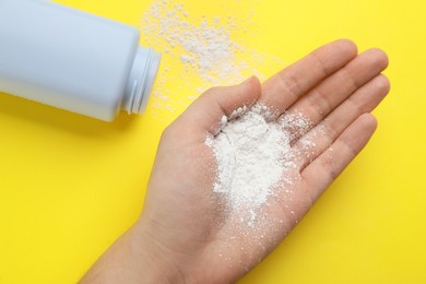Photo of Woman with dusting powder on yellow background, top view