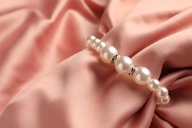 Elegant bracelet with pearls on pink silk, closeup