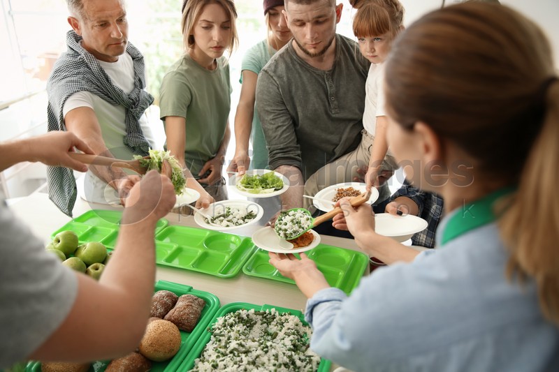 Volunteers serving food for poor people indoors