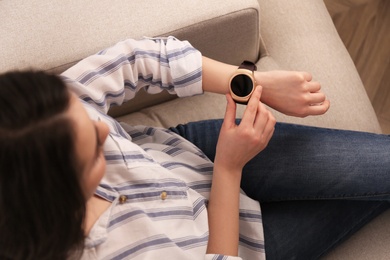 Young woman using smart watch at home, top view