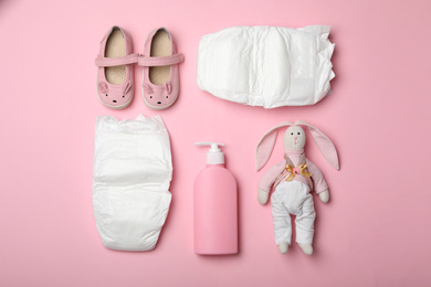 Diapers and baby accessories on pink background, flat lay