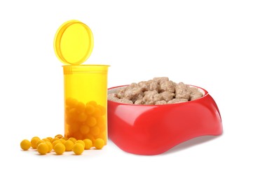 Wet pet food in feeding bowl and vitamin pills on white background