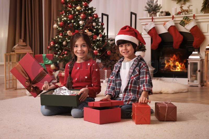 Happy children opening Christmas gifts on floor at home