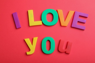 Phrase I Love You made of colorful letters on red background, flat lay