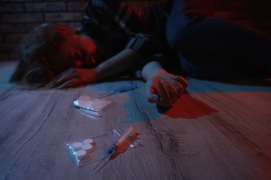 Addicted woman lying indoors, focus on different drugs