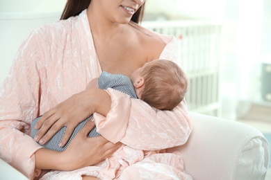 Young woman breastfeeding her baby in nursery, closeup