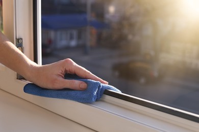 Photo of Woman cleaning window frame with rag at home, closeup. Space for text