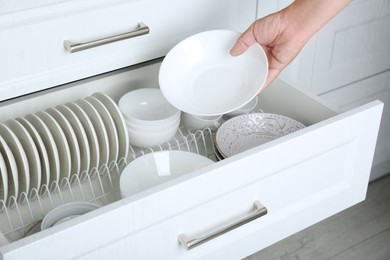 Photo of Woman taking ceramic bowl from drawer in kitchen, closeup