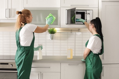 Professional janitors cleaning kitchen with supplies indoors