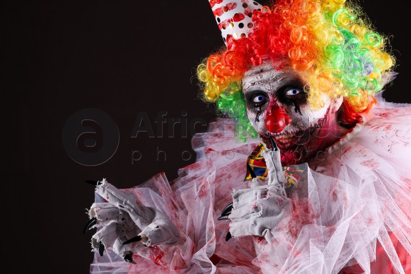 Terrifying clown on black background, space for text. Halloween party costume