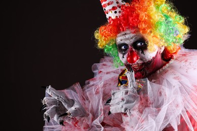 Photo of Terrifying clown on black background, space for text. Halloween party costume