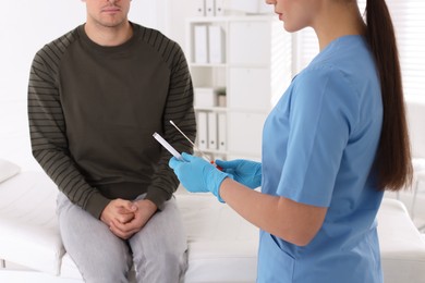 Doctor taking sample for STD testing from man in clinic, closeup