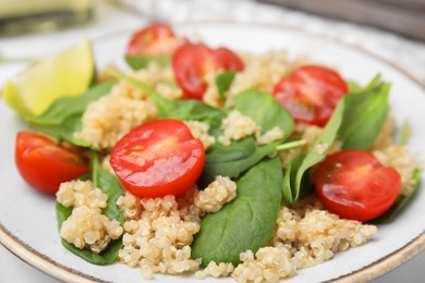 Photo of Delicious quinoa salad with tomatoes and spinach leaves, closeup