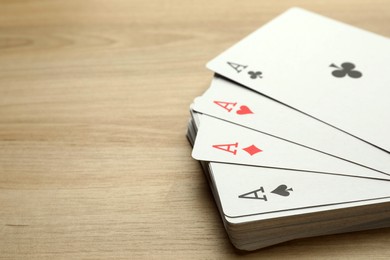 Photo of Four aces playing cards on wooden table, closeup. Space for text