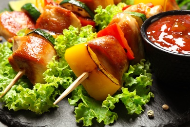 Delicious chicken shish kebabs with vegetables on slate plate, closeup
