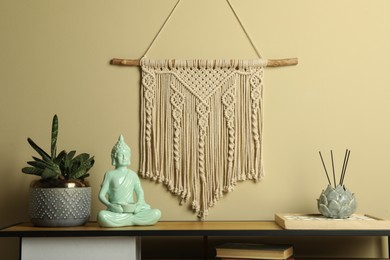 Beautiful macrame hanging on beige wall in room. Decorative element