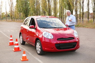 Instructor near car, outdoors. Passing driving license exam
