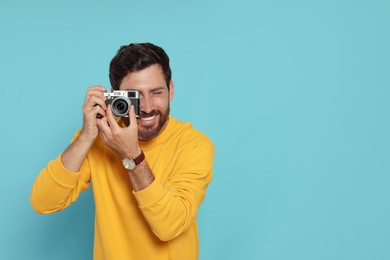 Photo of Man with camera taking photo on light blue background, space for text. Interesting hobby