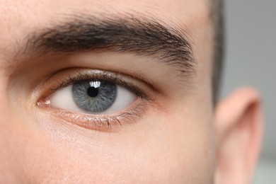 Photo of Closeup view of young man with beautiful grey eyes on blurred background