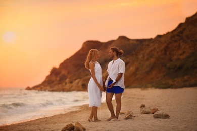 Young couple walking on beach at sunset