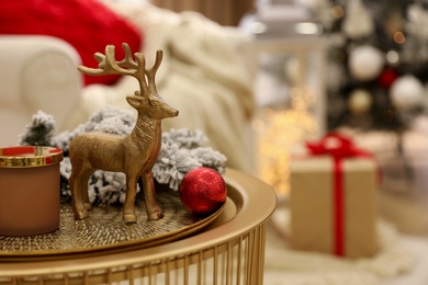 Christmas composition with decorative reindeer on golden table in room, closeup. Space for text