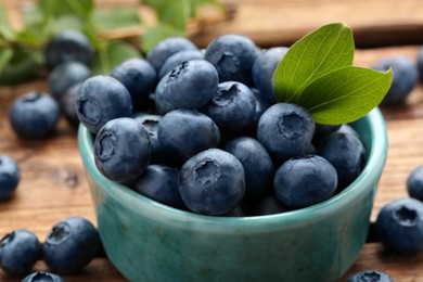 Tasty fresh blueberries and green leaves on table, closeup