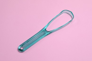 One turquoise tongue cleaner on pink background