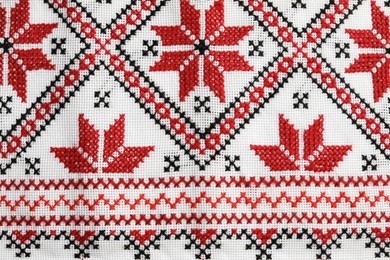 Photo of Traditional Ukrainian embroidery on white canvas as background, closeup. National handicraft