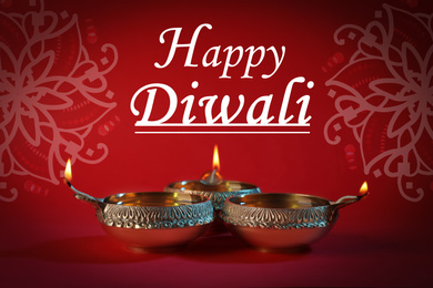 Inscription Happy Diwali and clay lamps on color background