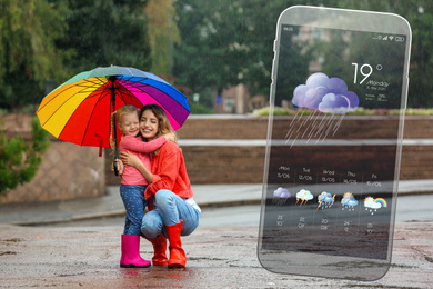 Happy people under rain outdoors and smartphone with open weather forecast app 