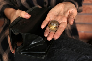 Poor woman with wallet counting coins, closeup