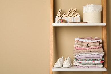 Baby clothes and accessories on wooden rack, space for text