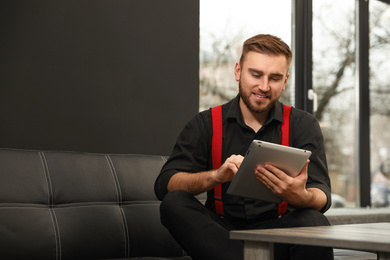 Young business owner with tablet on couch indoors