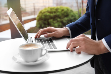 Photo of Businessman working with laptop in outdoor cafe, closeup. Corporate blog