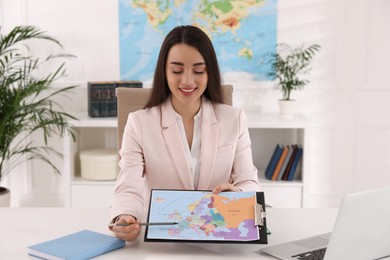 Happy manager showing map at desk in travel agency