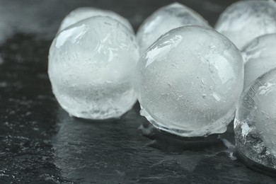 Photo of Many melting ice balls on black table, closeup