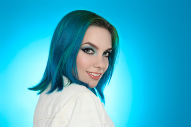Young woman with bright dyed hair on light blue background