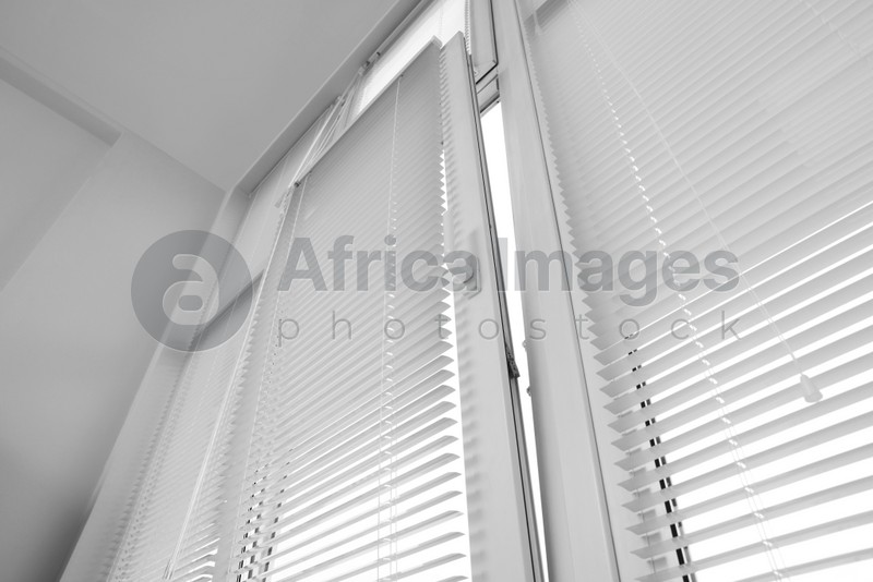 Photo of Stylish window with horizontal blinds in room, low angle view