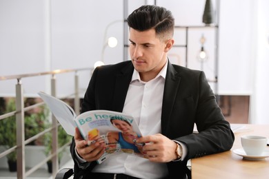 Man reading magazine at table in office